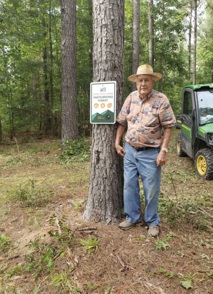 ncx landowner from south carolina stands next to his ncx property sign in the forest